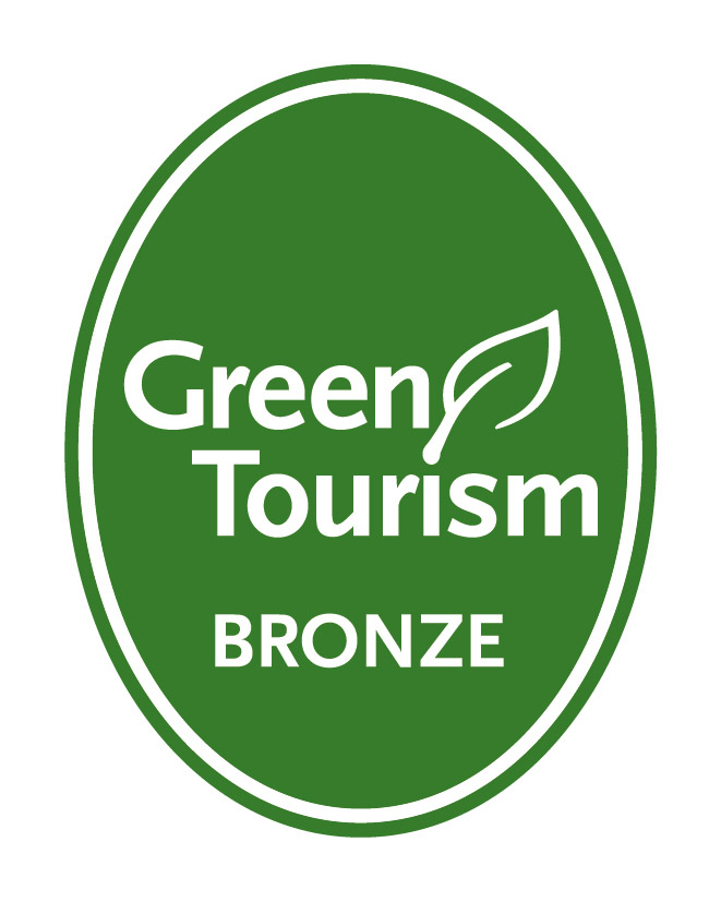 Green Tourism bronze logo - white text on a green oval with a leaf